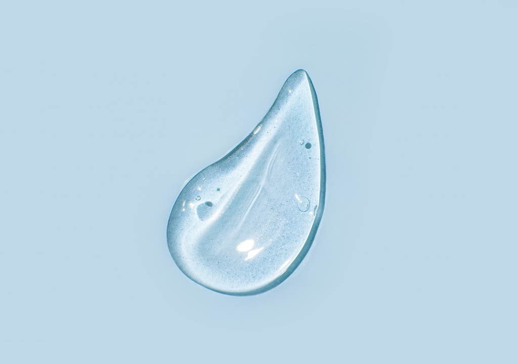 A droplet of panthenol on a blue background. Read about the benefits of pantheon for hair, skin, and body care at PillowtalkDerm.